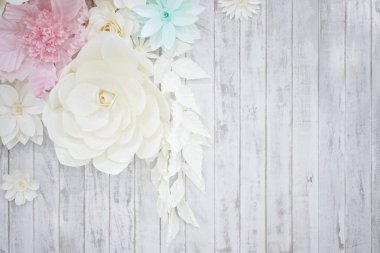 Pastel kağıt çiçek; krem, beyaz, pembe, yeşil, mavi beyaz ahşap plaka arka plan üzerinde el zanaat sanatla.