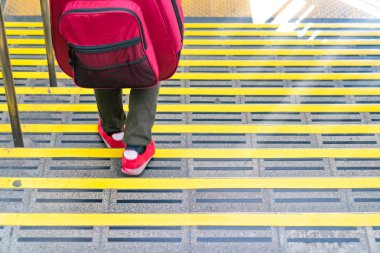 Japon gitar sırt çantası ile tren istasyonunda merdiven aşağı sırt üstü yürüyüş.