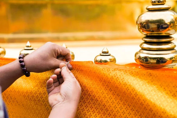 male\'s hand try to attach pin clasp to yellow cloth together for cover the pagoda barricade. In Thai traditional event., North of Thailand.