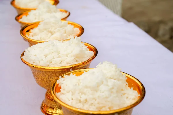 cooked Jasmine rice in the gold pan on the white table ready for Thai Buddhism traditional ceremony.