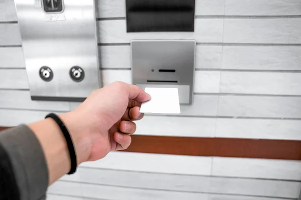 securing lift or elevator access control, man\'s hand is holding a key card lay up to insert in card hold for unlocking elevator doors before up or down.