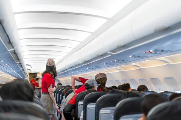 air hostess in red uniform services and checks for all correct at all around the passenger seat