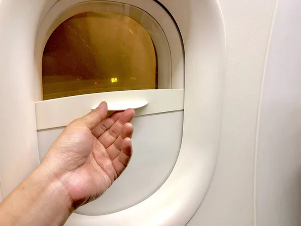 close up hand holding the cover plane window to close and open