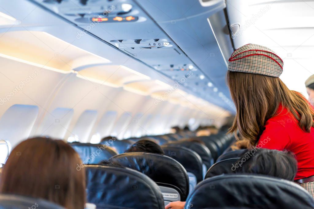 air hostess in red uniform services and checks for all correct at all around the passenger seat