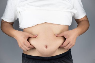 Asyalı adam göbek gösteren ve Yağ yakalamak ellerini yükselterek