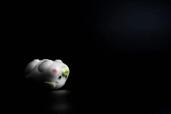 Isolated sad piggy bank on the black background with copy space.