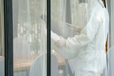 Önleme giysisindeki profesyonel teknik adam sterilizasyon çözeltisi püskürttü.