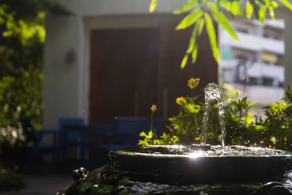 从竹竿到小喷泉的衣服 装在绿色的老式罐子里 装饰在花园里 具有阳光的效果 — 图库照片