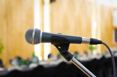 Kürsünün yanındaki mikrofona yakın uzun siyah masa yemeği zamanı tungsten ışığı altında..