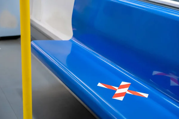 blue seat row in the train with crossed marking tape in Coronavirus (COVID-19) period. It means Social Distancing in transportation.