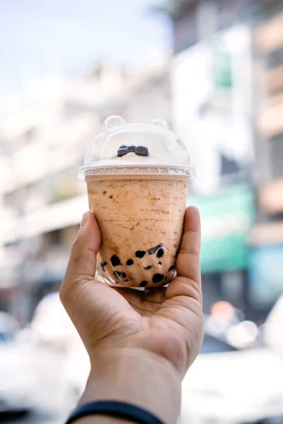 泡ボールアイスミルクティー手にぼかしアジアの建物の背景と — ストック写真
