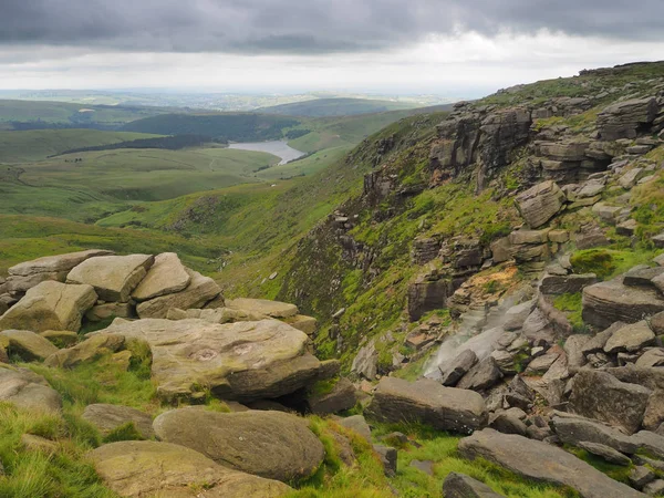 Kinder Downfall overlooking reservoir with wind blowing waterfall into the air, Peak District, UK