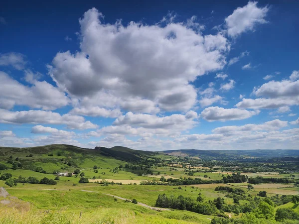 View over Hope Valley and Lose Hill with billowing white clouds and blue sky, Peak District, UK