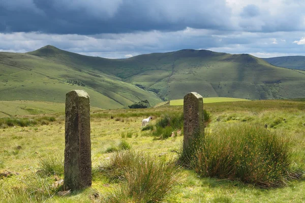 Vista sulle montagne illuminate dal sole e sui cancelli rocciosi con nuvole scure sopra la testa, Peak District, Regno Unito Fotografia Stock