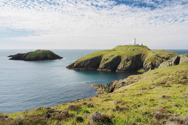 Маяк Strumble Head Lighthouse на Ynys Meicel з білими хмарами, Пембрукшир, Уельс. Стокове Зображення