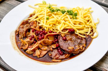 Kızılcık ve ev yapımı spaetzle ile kavrulmuş geyik ve yaban domuzu