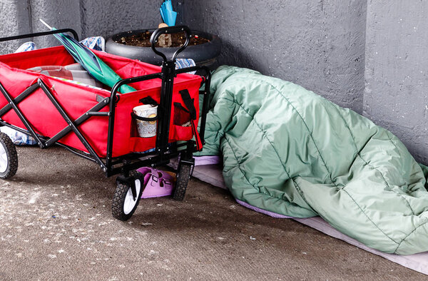 Homeless person sleeping on the street in the corner of a building in the Hafen City quarter of Hamburg, Germany 