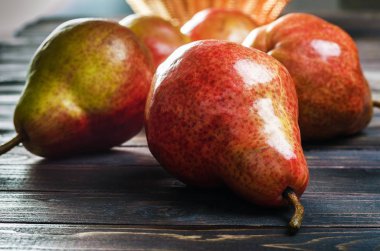 Koyu ahşap rustik arka plan üzerinde bir sepet içinde parlak kırmızı-sarı armut. Sonbaharda hasat meyve.