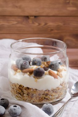 Doğal yoğurt, yaban mersini, fındık ve kuru meyve bir cam kavanoza ile müsli