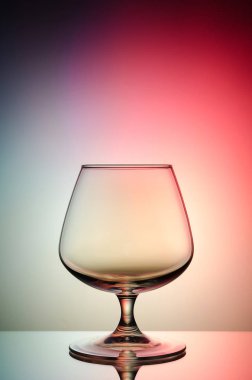 Boş bardak konyak renk, degrade arka plan için. Ayna yüzey. Konsept: parlak, neşeli, kulüp hayat. 