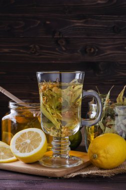 limon ve koyu ahşap arka plan üzerine bir bardak ballı bitki çayı