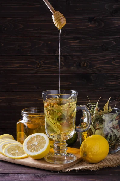 herbal tea with lemon and honey in a glass on a dark wooden background