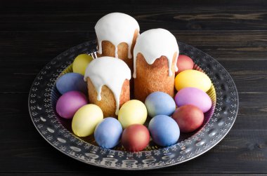 Paskalya natürmort karanlık, ahşap arka plan üzerinde. Paskalya kek ile boyalı tavuk yumurta bir tepside