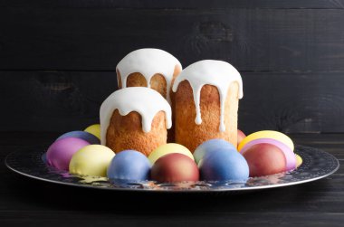 Paskalya natürmort karanlık, ahşap arka plan üzerinde. Paskalya kek ile boyalı tavuk yumurta bir tepside