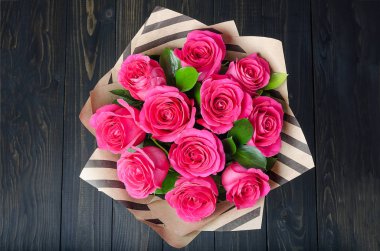 Koyu ahşap arka plan üzerinde parlak pembe gül buketi