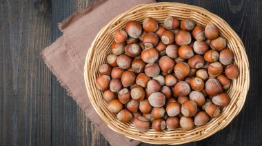 Bir karanlık, rustik, ahşap arka planda bir kil kase fındık.