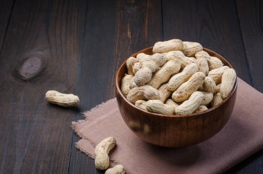 Ahşap kase bir karanlık, rustik, ahşap arka plan kabuğuna fıstık.