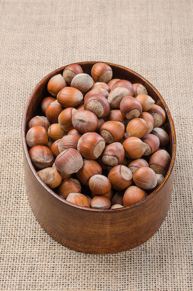 Орешки в кожуре на легком мешковине в деревянной чаше
.
