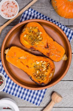 Fırında kabak kil çanak üzerinde mavi bir peçeteye ahşap, gri bir rustik arka plan kekik ile.