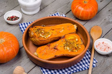 Fırında kabak kil çanak üzerinde mavi bir peçeteye ahşap, gri bir rustik arka plan kekik ile.