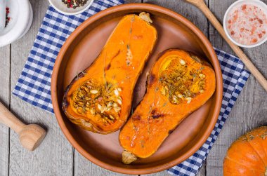 Fırında kabak kil çanak üzerinde mavi bir peçeteye ahşap, gri bir rustik arka plan kekik ile.