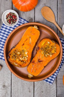 Fırında kabak kil çanak üzerinde mavi bir peçeteye ahşap, gri bir rustik arka plan kekik ile.