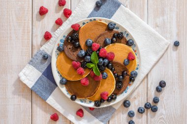 Çikolatalı ve vanilyalı kek ahududu, böğürtlen, yaban mersini ile bir tavada.