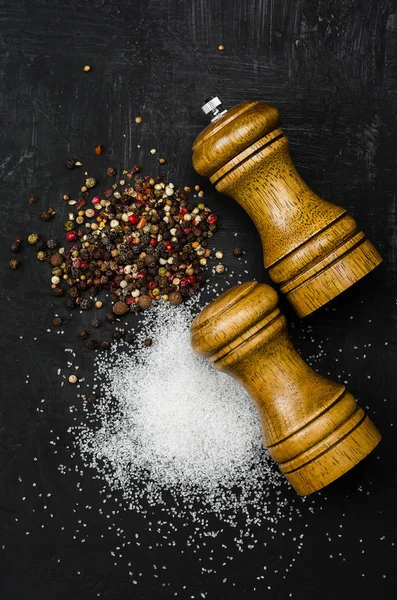 Wooden salt shaker and pepperbox on black chalk board.