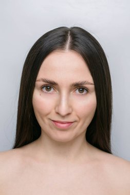Güzel bir genç kadın, esmer, düz saçlı kahverengi gözlü, gülümseyen, makyajsız. 