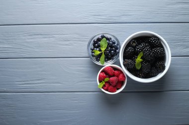 Ahşap arka plan üzerinde kase çilek. Ahududu, frenk üzümü, çilek, yaban mersini, Bektaşi, böğürtlen ve nane bileşimi. Sağlık, diyet, Bahçe. Hasat kavramı