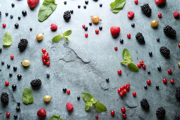 Top view, flat lay. Food background. Composition of raspberry, currant, strawberry, blueberries, gooseberries, blackberries and mint on a gray background with space for text