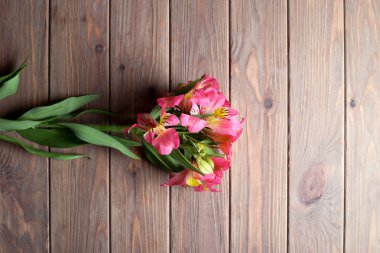 Alstroemeria kahverengi ahşap arka plan üzerinde bir delikanlı. Yukarıdan görüntülemek