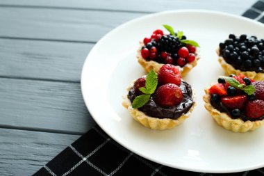 Masa örtüsü gri ahşap zemin üzerine çikolata kremalı kek lezzetli sulu berry. Yan görünüm