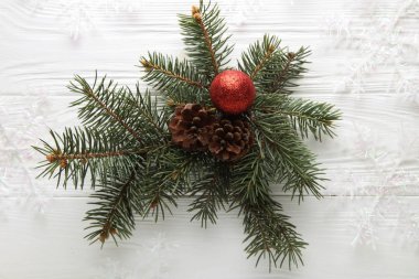 Beyaz ahşap zemin üzerinde Noel kompozisyon. Noel oyuncak, xmas süslemeleri, kar ince tabakalar, çam dalları koniler ile. Üstten görünüm