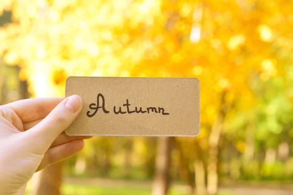 Texte d'automne sur une carte. Fille tenant la carte dans le parc d'automne au soleil — Photo