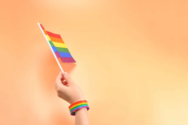 Bandeira LGBT na mão da mulher no fundo laranja. Espaço de cópia . — Fotografia de Stock