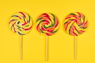 Sarı bir arka plan üzerinde renkli şeker. Lolipop. Üst te. Kopya