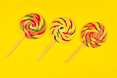 Sarı bir arka plan üzerinde renkli şeker. Lolipop. Üst te. Kopya