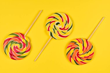 Sarı bir arka plan üzerinde renkli şeker. Lolipop. Üst te. Kopya