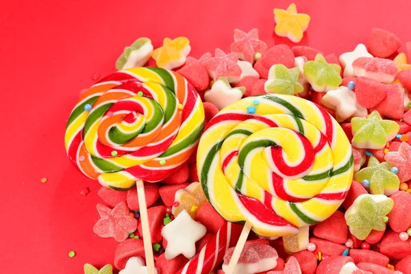 Surtido de coloridos caramelos de goma y piruleta sobre fondo rojo . — Foto de Stock